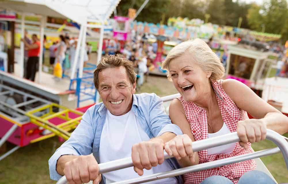 An older couple having fun on a fast moving fairground ride, holding on tight.