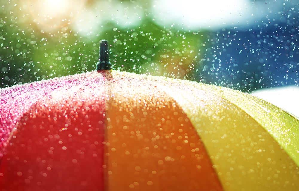 Rain drops bouncing of the surface of a colourful umbrella. 