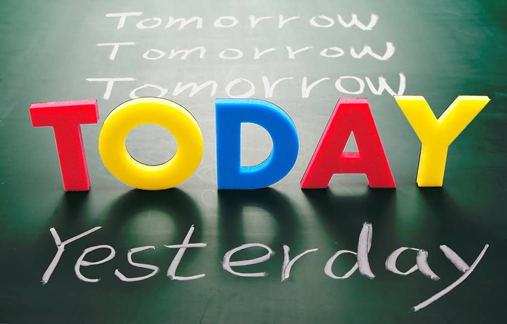 The word 'TODAY' spelt out in 3D coloured, plastic letters. The letters sit on a flat chalk board in between the words 'yesterday' and 'tomorrow'.