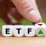 Hand is turning a dice and changes the direction of an arrow symbolizing that the value of an ETF (Exchange Traded Fund) is going up (or vice versa)