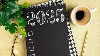 New year resolutions 2025 on desk. 2025 resolutions list with notebook, coffee cup on table.